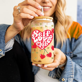 Wholesale 20oz glass cups with bamboo lid and glass straw featuring Self Love Club and empowering red heart graphics.
Self Love Club wholesale 20oz glass cups with bamboo lid and glass straw for self love, self growth, and empowerment gifts.