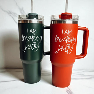 Two insulated travel mugs, one green and one red, with humorous text on a white background.