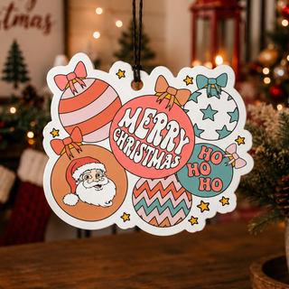 A festive Christmas ornament-shaped hanging tag with colorful holiday illustrations and the words “Merry Christmas” and “Ho Ho Ho,” displayed on a wooden table in a warmly lit Christmas living room setting.