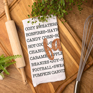 white cotton towel with black fall words and glitter script
modern farmhouse fall kitchen towel on cutting board
cozy fall sayings kitchen towel on white background
autumn word art tea towel with orange glitter fall text