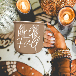 hello fall mug next to stack of sweaters
hello fall coffee cup on kitchen island
hello fall mug on round wooden riser
hello fall mug with neutral fall tablescape
hello fall mug on rustic bench with rain boots
hello fall mug next to fall wreath decor