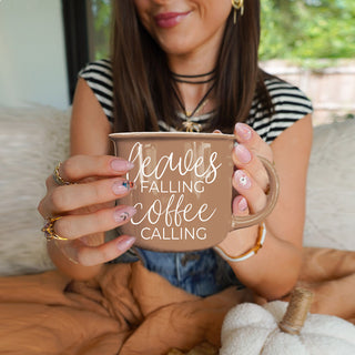 giftable autumn mug for coffee and fall leaf lovers
fall and autumn kitchen decor with brown quote mug
leaves falling coffee calling mug close up
brown fall coffee mug with autumn leaves decor
cozy autumn mug with leaves falling coffee calling phrase