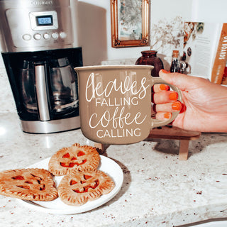 leaves falling coffee calling mug on marble countertop
autumn coffee cup with warm brown tones and fall decor
brown fall mug with chain and pumpkin styling
leaves falling coffee calling mug for fall coffee bar