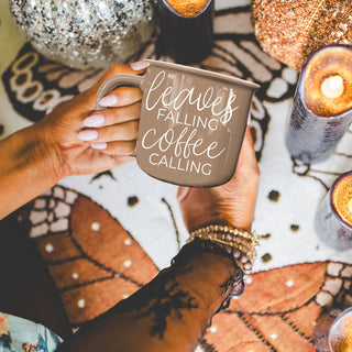 fall leaves coffee cup next to candle and pumpkin
brown cozy fall mug for autumn mornings
leaves falling coffee calling mug in halloween and fall setup
autumn gift idea brown quote coffee mug
fall themed ceramic mug with leaves and coffee phrase