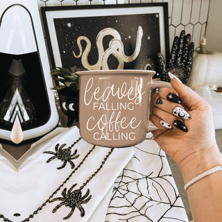 autumn table setting with brown coffee mug and napkin
cozy couch scene with brown fall mug and knit pillow
leaves falling coffee calling mug on open book and throw
brown autumn mug with acorns and pinecones accents