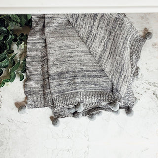 Gray throw blanket with pom poms for couch